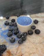 Colorwayz Blueberry Cotton Candy Sugar spilling onto a marble surface surrounded by blueberries, highlighting its natural ingredients and fruity flavor for making candy floss.