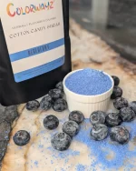 Bowl of Colorwayz Blueberry Cotton Candy Sugar surrounded by fresh blueberries, showcasing natural blueberry flavor and a soft, muted blue color.