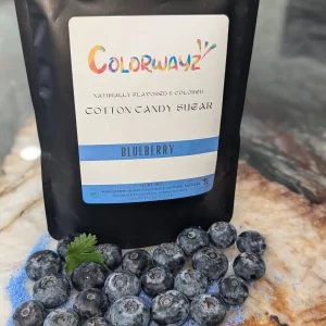 Colorwayz Blueberry Cotton Candy Sugar bag next to a bowl of sugar and fresh blueberries, perfect for making soft blue cotton candy with natural food coloring