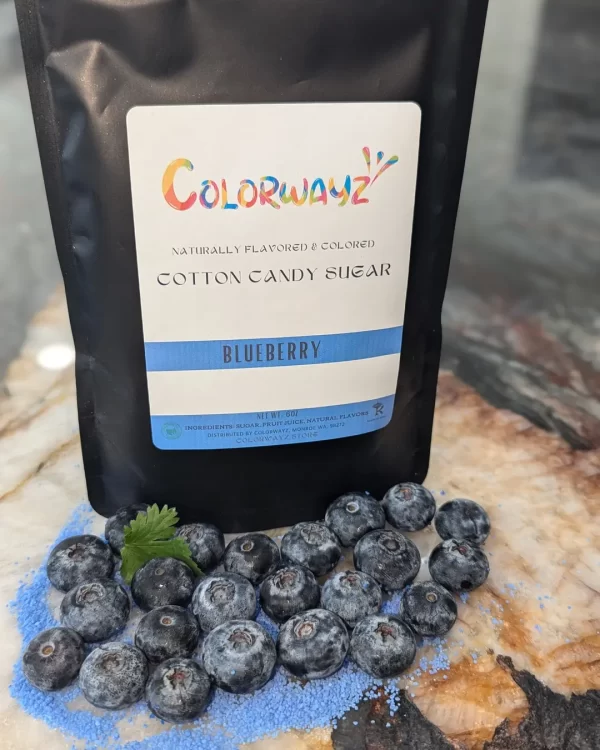 Colorwayz Blueberry Cotton Candy Sugar bag next to a bowl of sugar and fresh blueberries, perfect for making soft blue cotton candy with natural food coloring