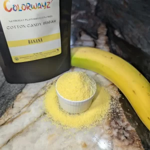 Colorwayz Banana Cotton Candy Sugar sprinkled around a small bowl, capturing the vibrant yellow color for delicious cotton candy creations.